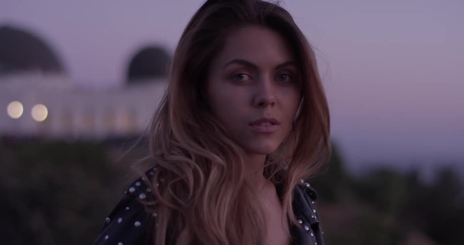 Woman stands outside at sunset staring