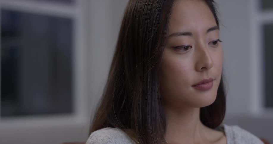 Woman sits in a room smiling and looking down