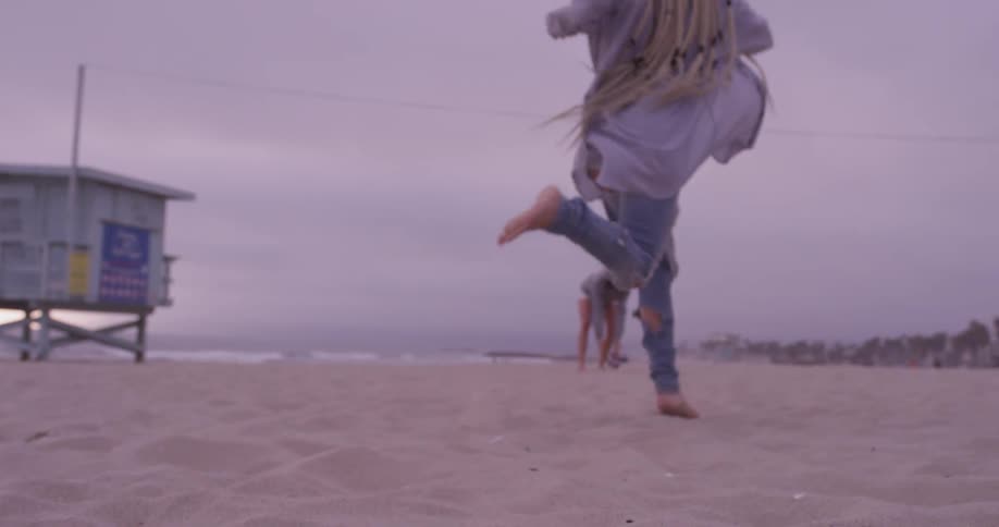 Woman kicking a football at the beach