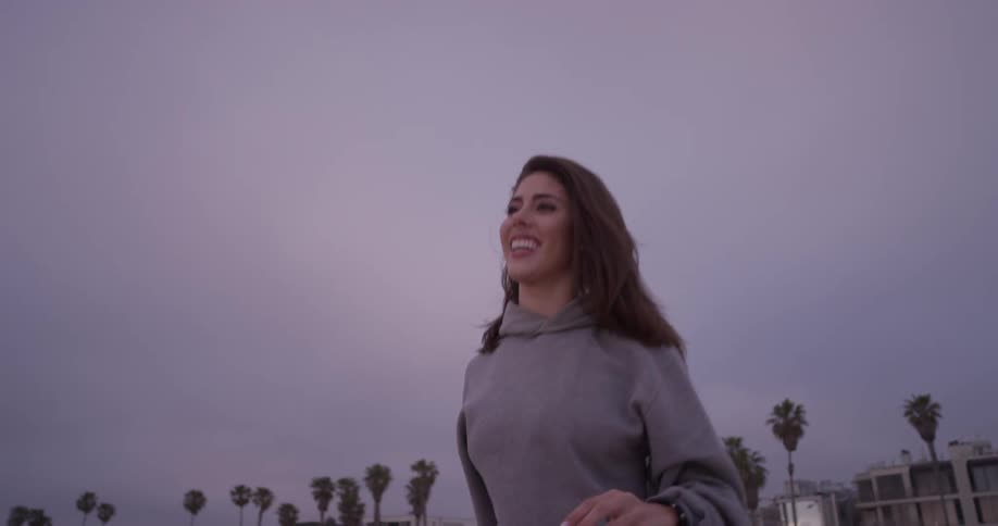 A woman throws a football in the air and waits to catch it