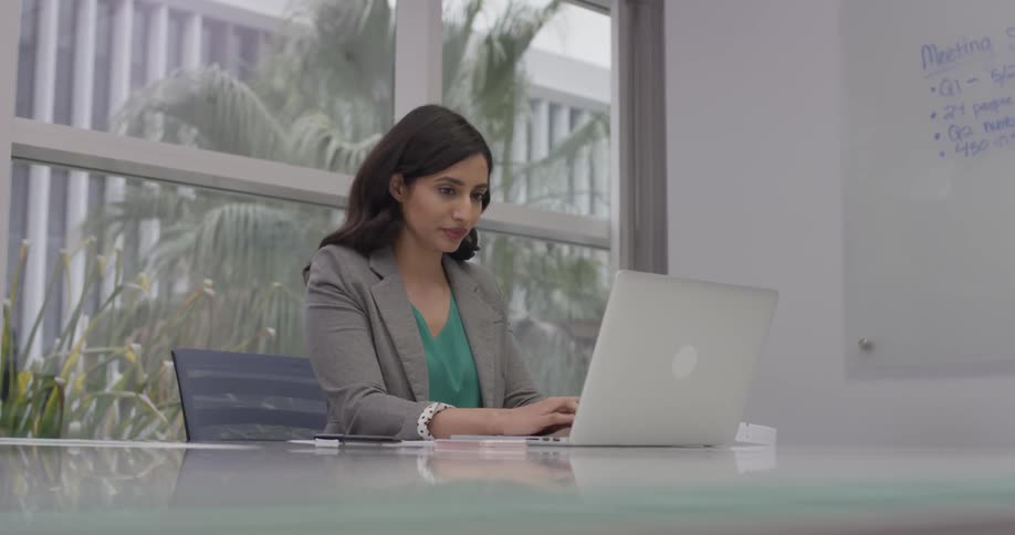 A woman typing on a laptop in an office