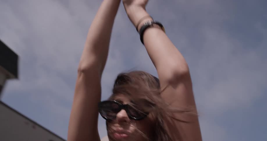 A woman is dancing and putting sunglasses on