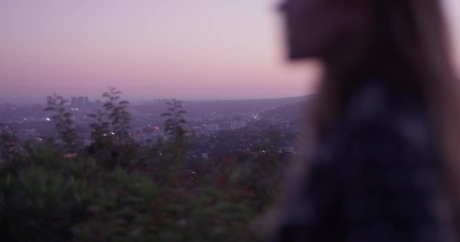 Woman walks at sunset looking around