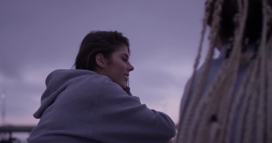Two women sits on the beach talking on a cloudy day