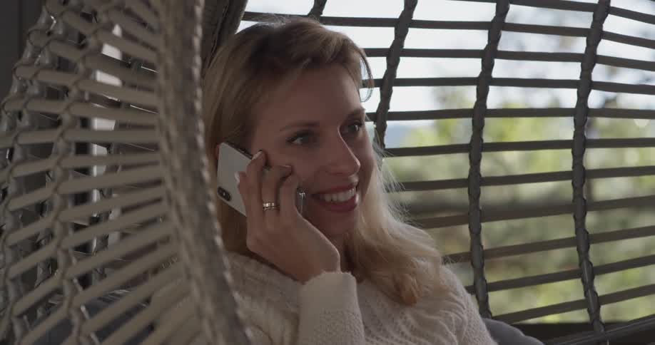 A woman sitting on a swing talking on the phone