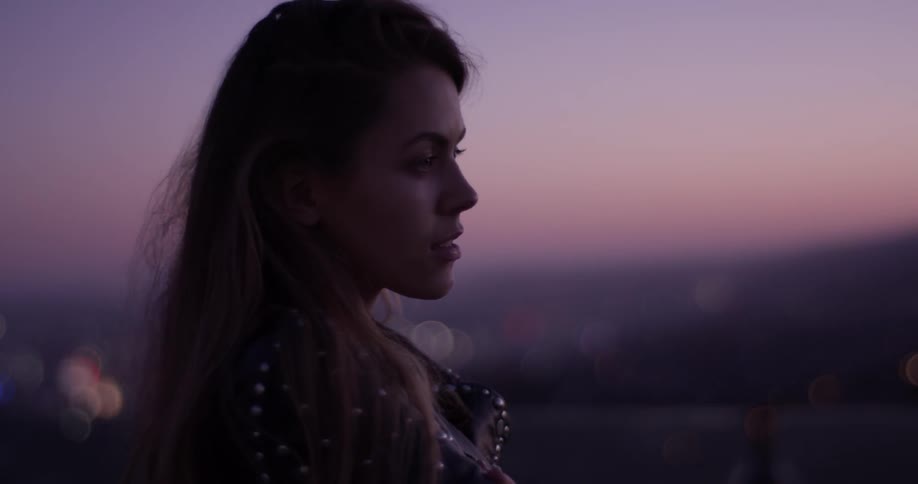 A woman is standing outside at dusk