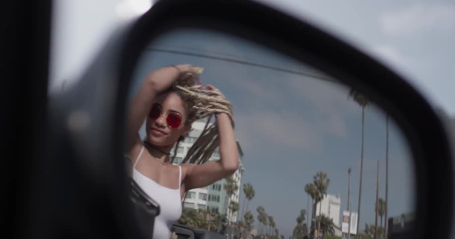Woman rides in a convertible waving her arms