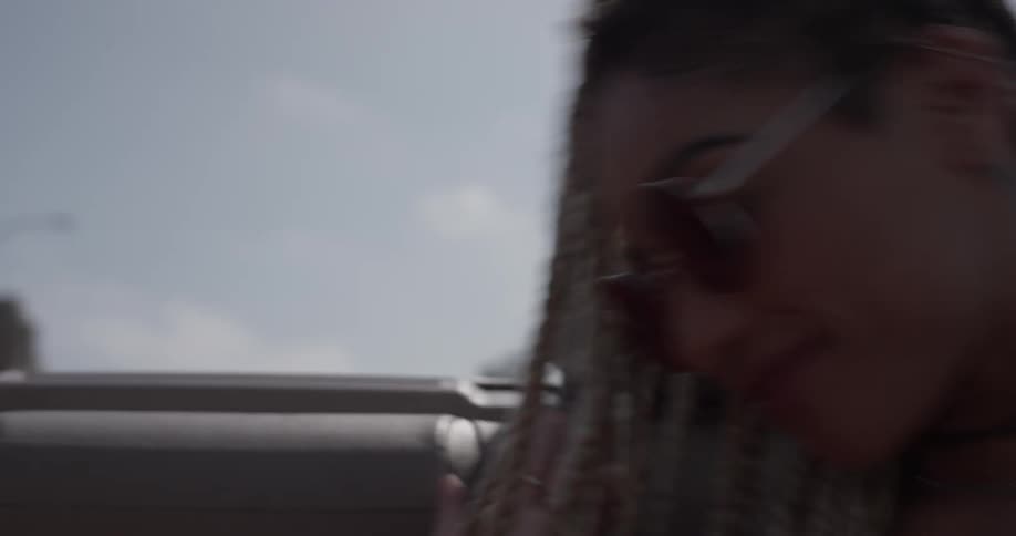 Woman smiles and waves her arms in a convertible
