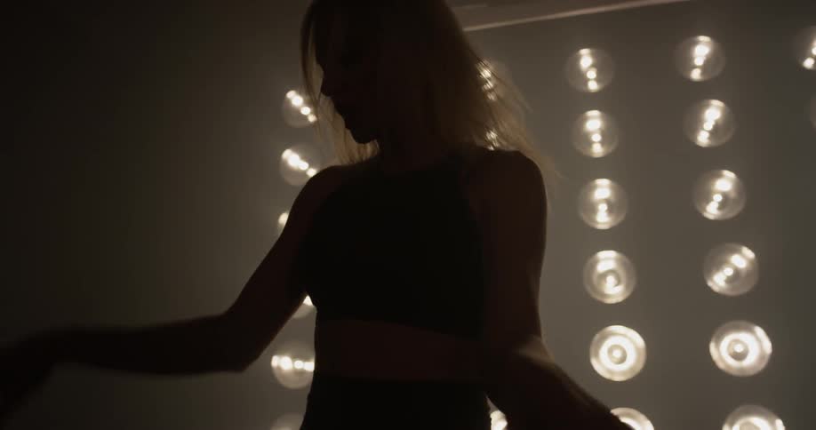 A woman jumping and dancing in front of lights
