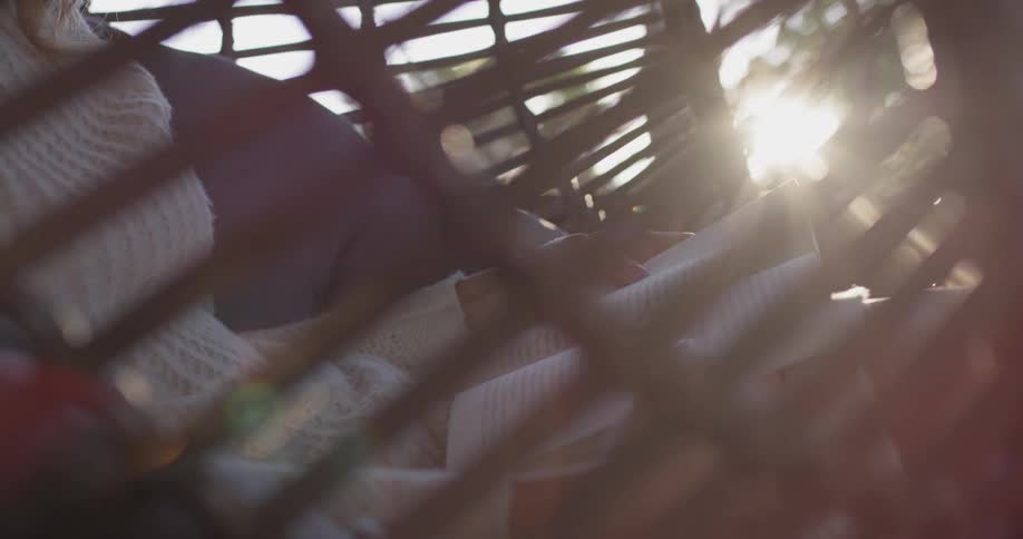 Sunlight shines on a woman reading in an outdoor swing
