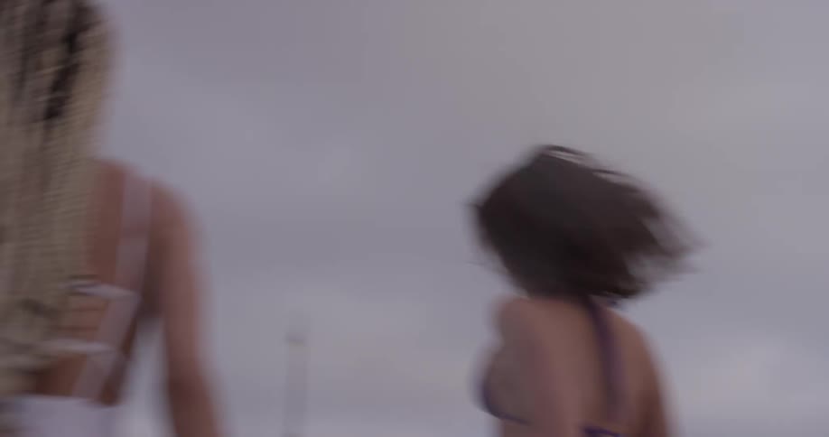 Two women run on the beach on a cloudy day