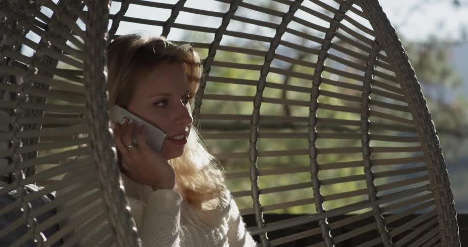 A woman rocking on a swing talking on the phone