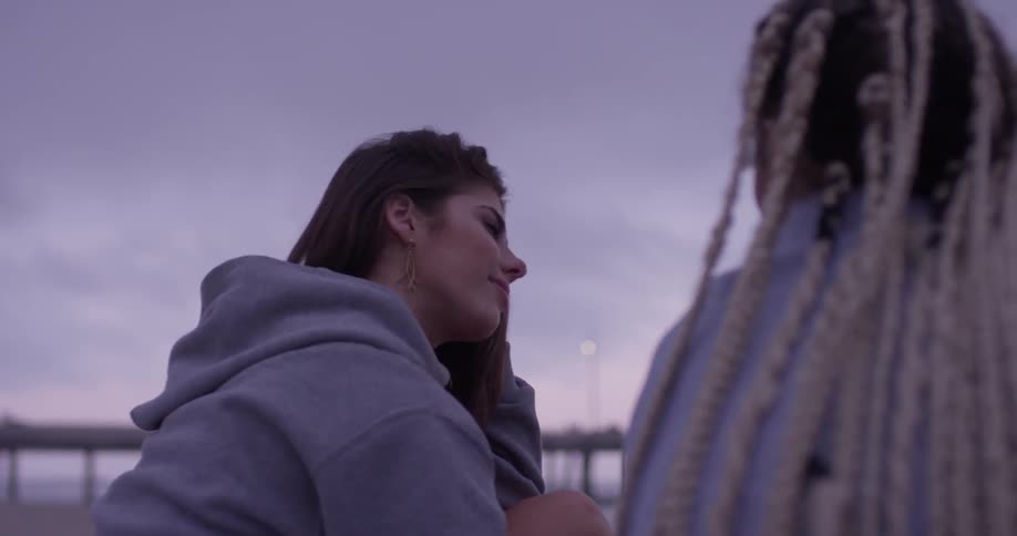 A woman in a sweatshirt talking to a woman beside her