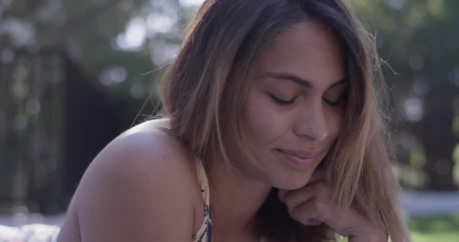 A woman  near trees playing with her hair and smiling