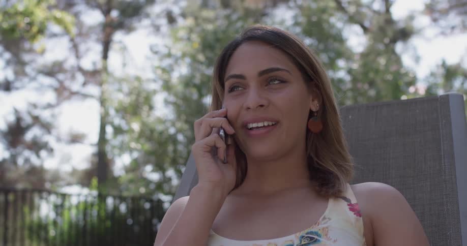 Smiling woman talks on the phone outside in a yard