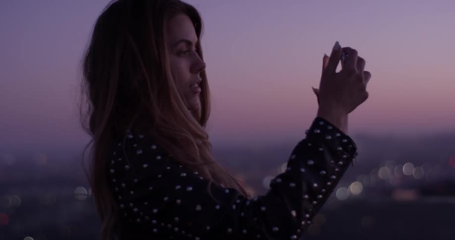 A woman stands in front of a vast city as she films herself