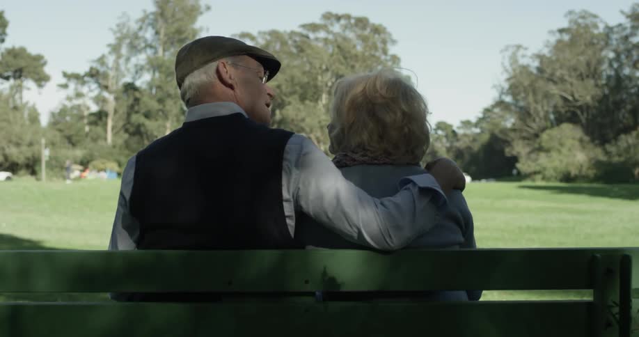 An old couple sitting at a park bench