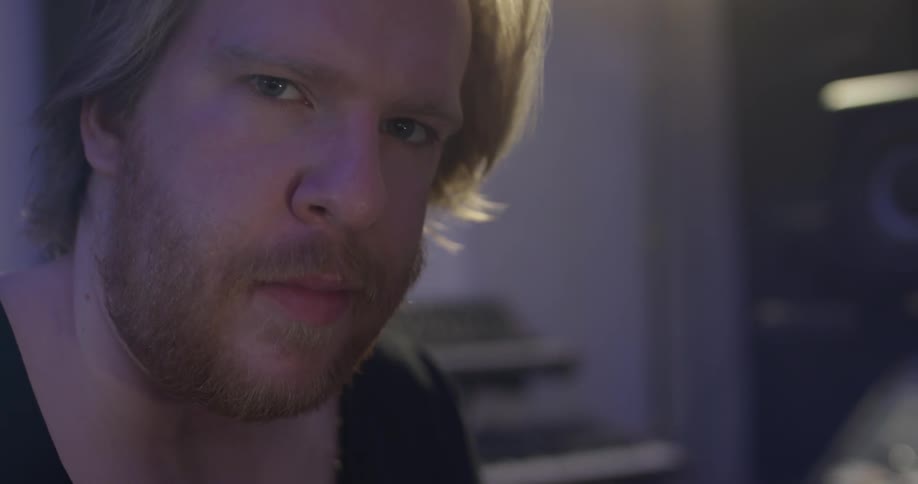 Man in dim room stares into camera