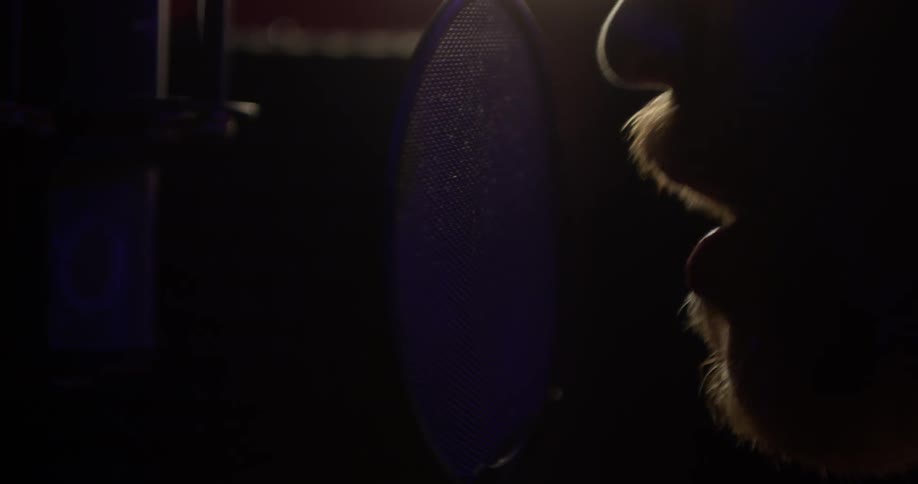 Man singing into a microphone in a studio