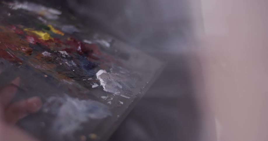 Someone holds a paint pallet as they paint