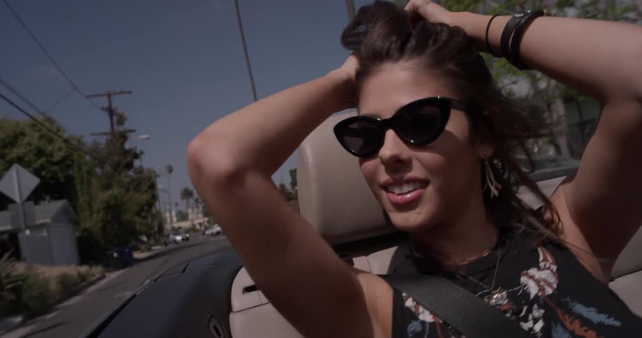 Woman rides in a convertible on a sunny day
