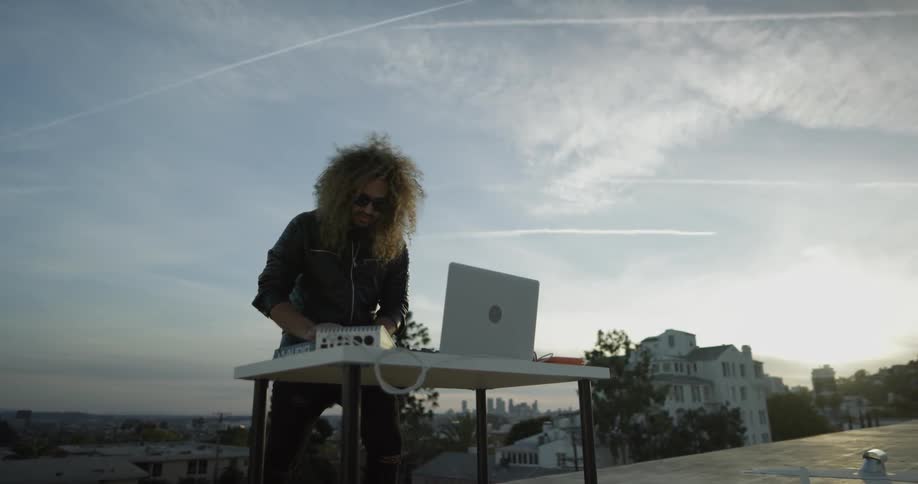 A man is working on his computer with music equipment