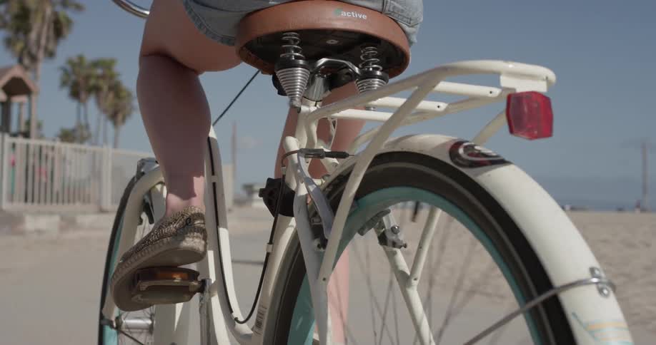 Woman rides a bike towards a playground