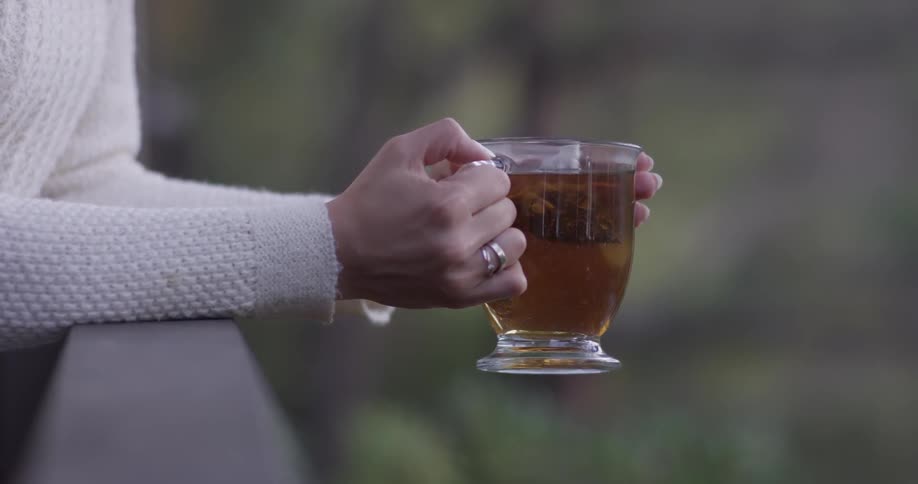 Woman holding a glass of tea outdoors