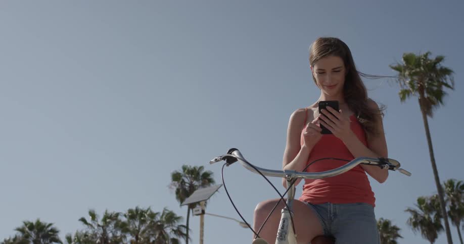 A woman is on her phone while sitting on a bicycle