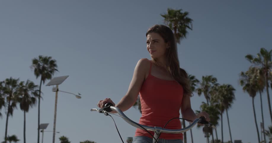 Woman riding a bicycle down the sidewalk next to the beach