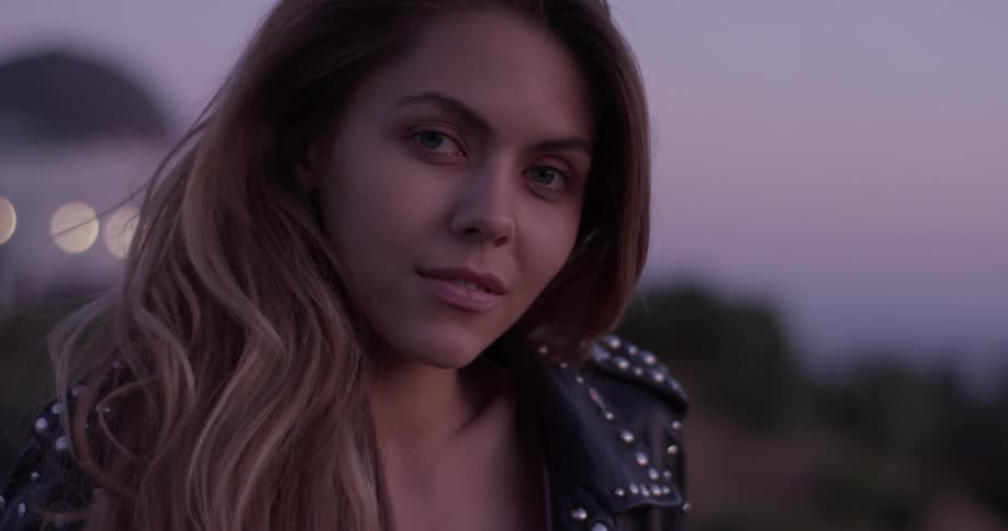Woman standing at the top of a hill at sunset