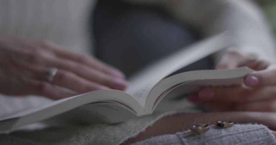 A woman is reading a book while sitting down