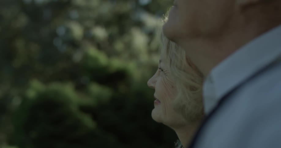 A man approaches a woman who looks very happy to see him and they stare at the natural beauty of the park they're at
