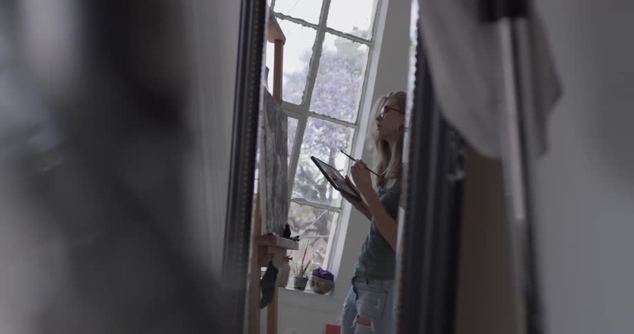 A woman painting on a canvas in a studio