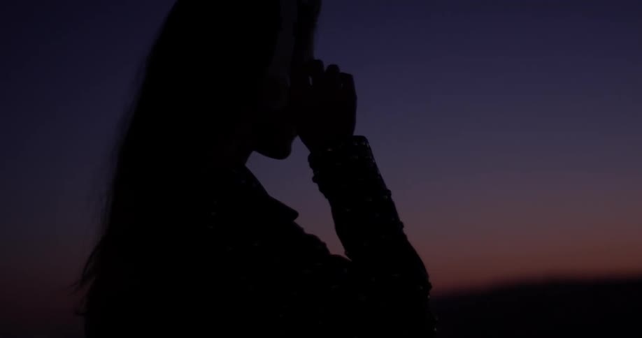 Woman walks outside at sunset