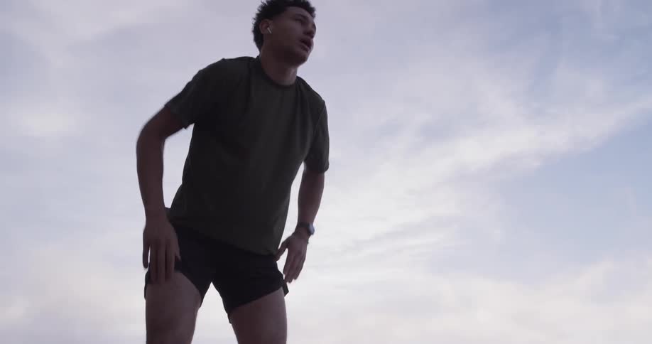 Man runs at sunrise and leans over breathing heavily