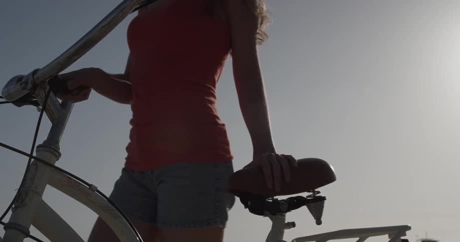 A woman walking her bicycle at dusk