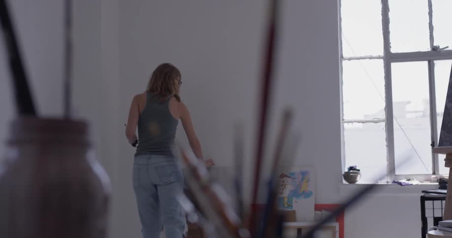 A woman picking up a canvas in a studio
