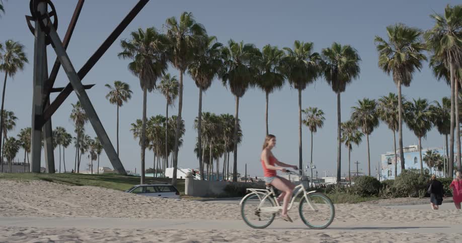 A woman rides a bike along the beach