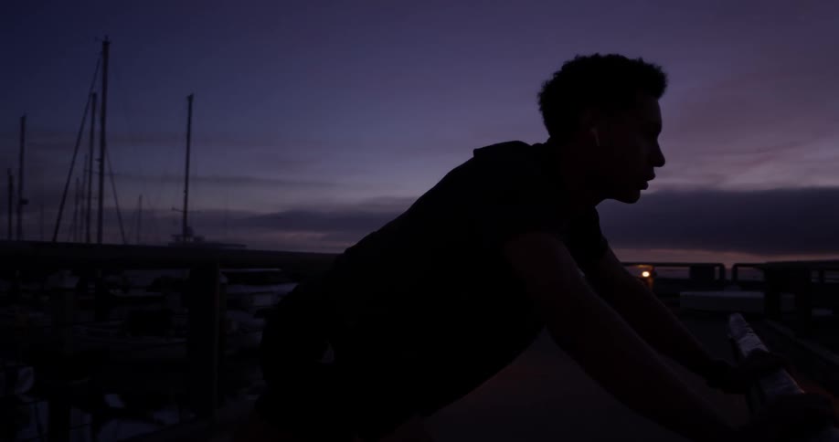 Man leans on a gate outside at night