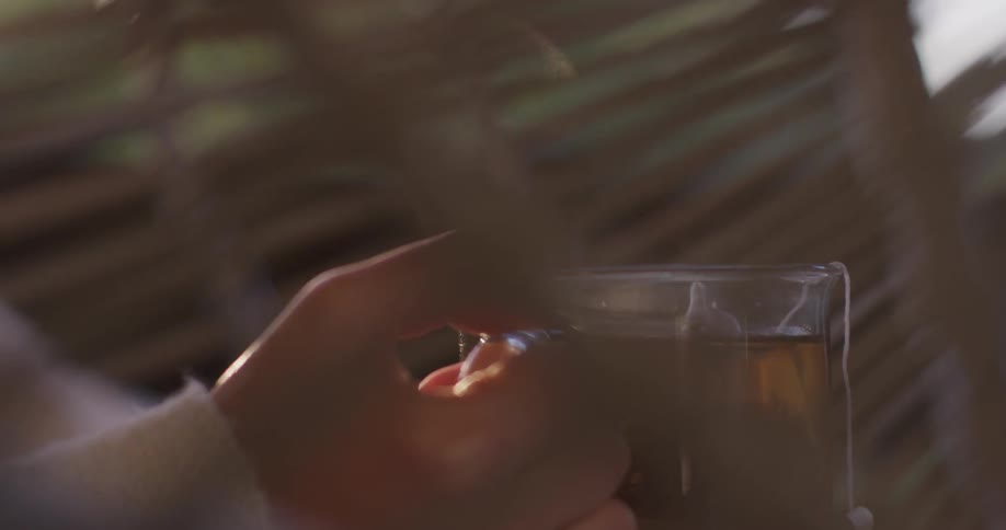A person holding a cup of tea outside