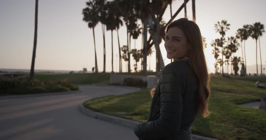 A woman shakes her hair and smiles as she walks