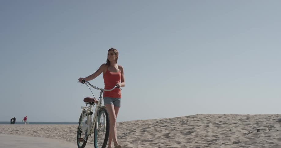 A woman walks her bike along the beach