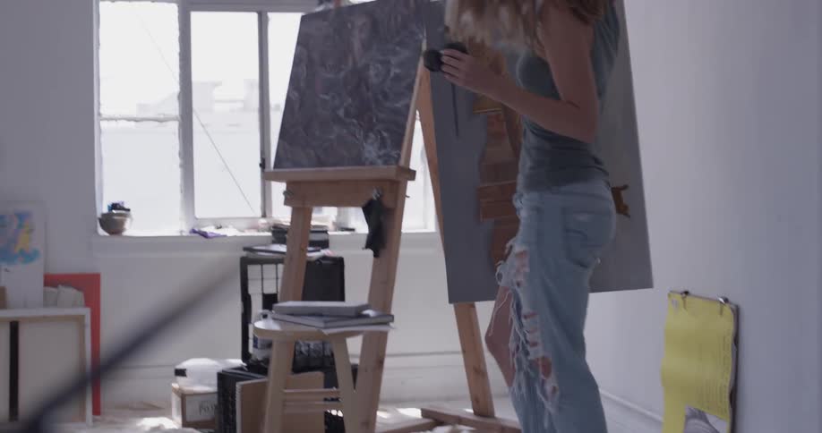 Woman picks up a painting and puts it next to other paintings