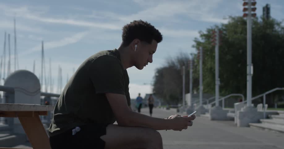 A man sitting on a bench looking at his cell phone