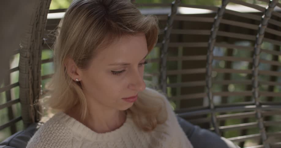Woman sits in a swing typing on a tablet