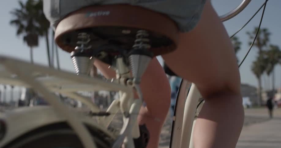 A woman wearing shorts bikes on a path near the beach
