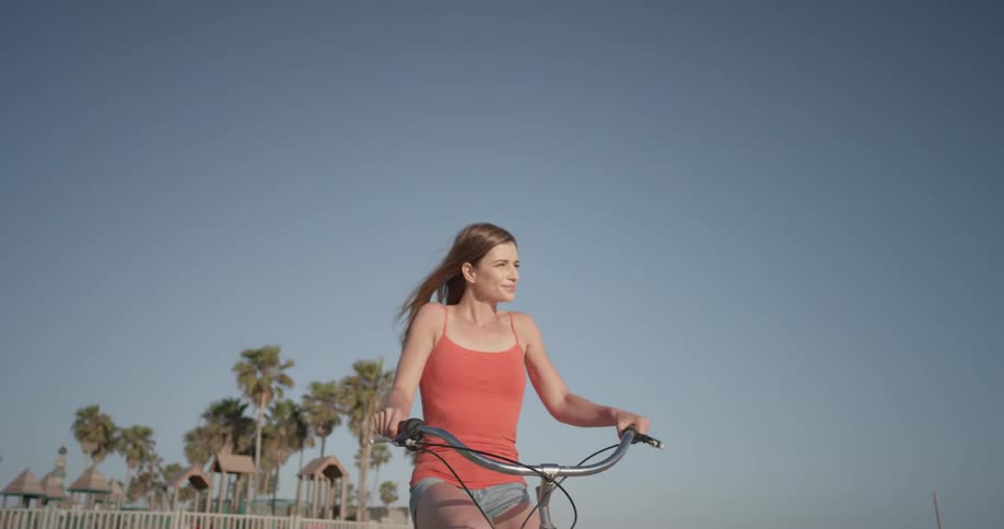 A woman riding a bike along a beach
