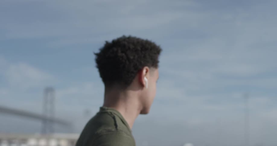 A man with headphones in his ears looking at the sea