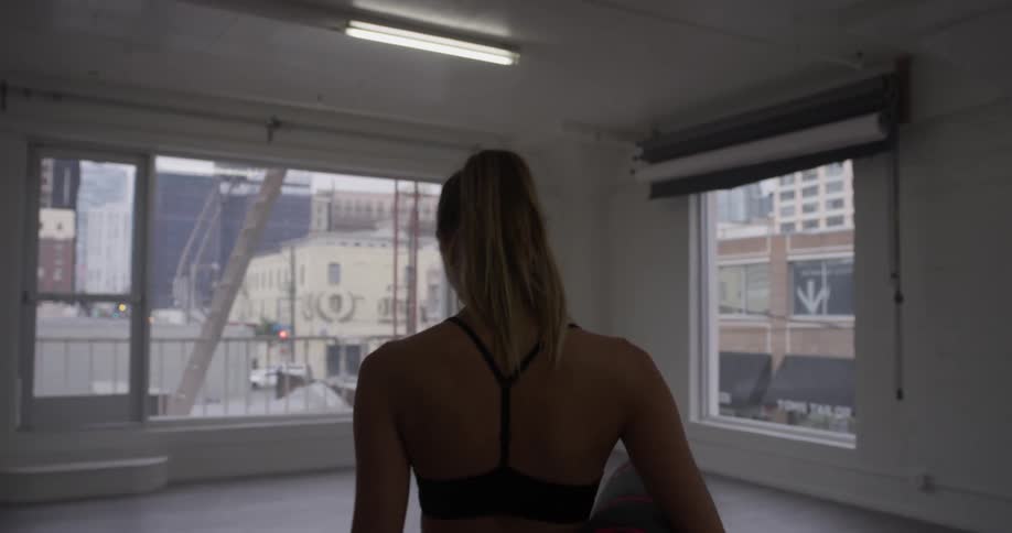 A woman walking into a studio carrying a yoga mat